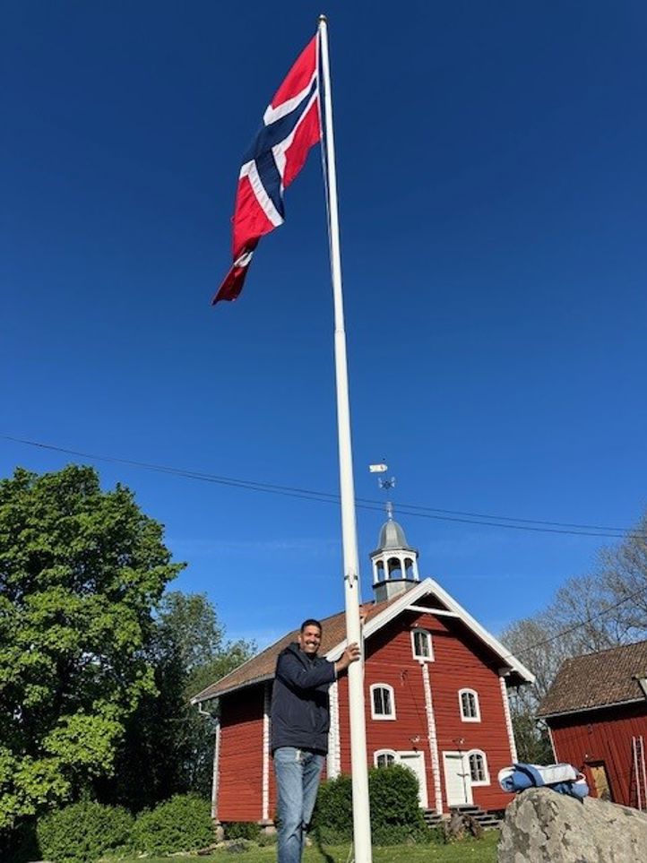 Driftsleder Mathi  som står ved siden av en flaggstang med et flagg på